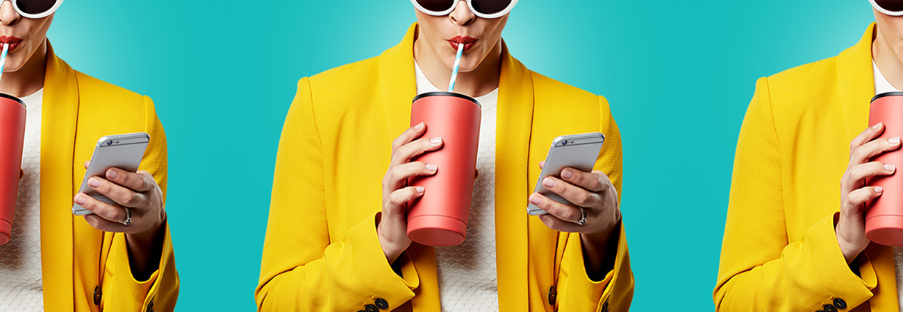 Repeating image of a woman in sunglasses and a yellow blazer drinking a beverage and looking at her phone