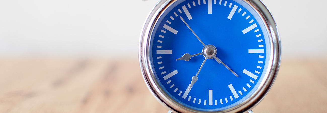 A silver alarm clock with a blue face