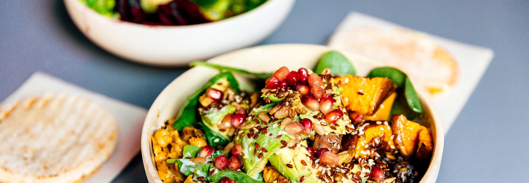 Two fresh salad bowls on a table with flatbreads