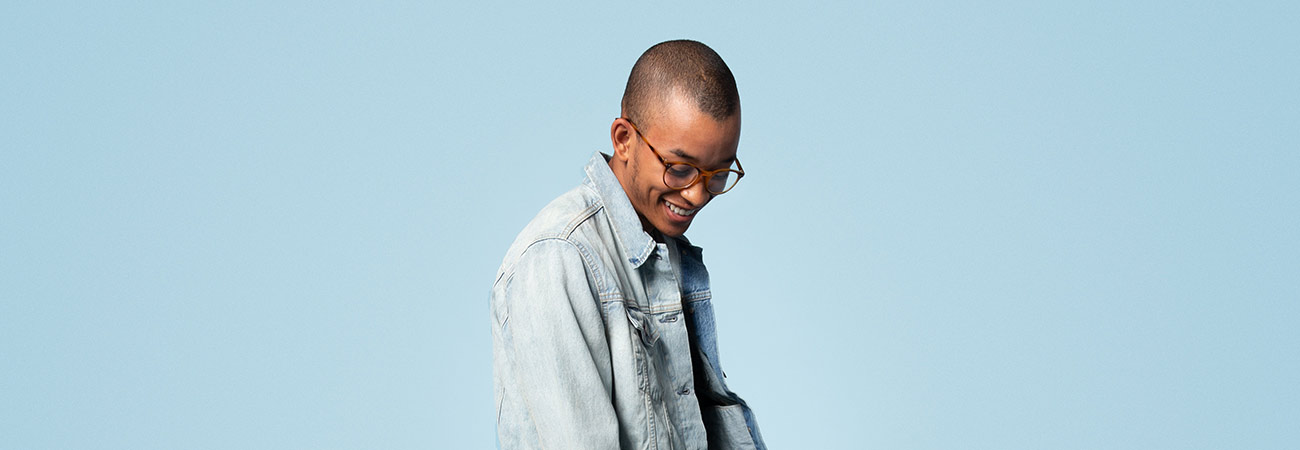A young man wearing glasses and a denim jacket