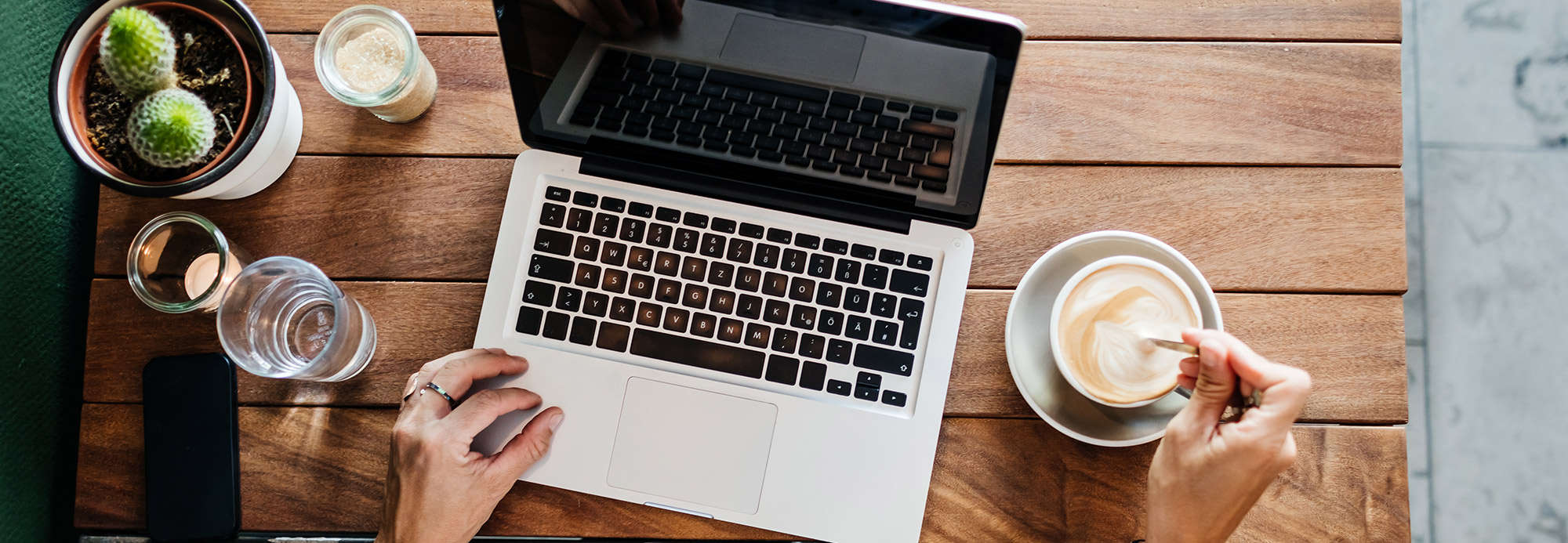 An overhead view of a laptop and coffee on a table