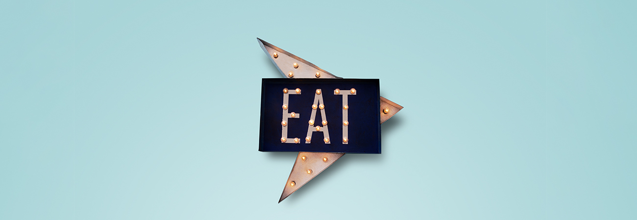 Illuminated arrow sign spelling out "Eat"