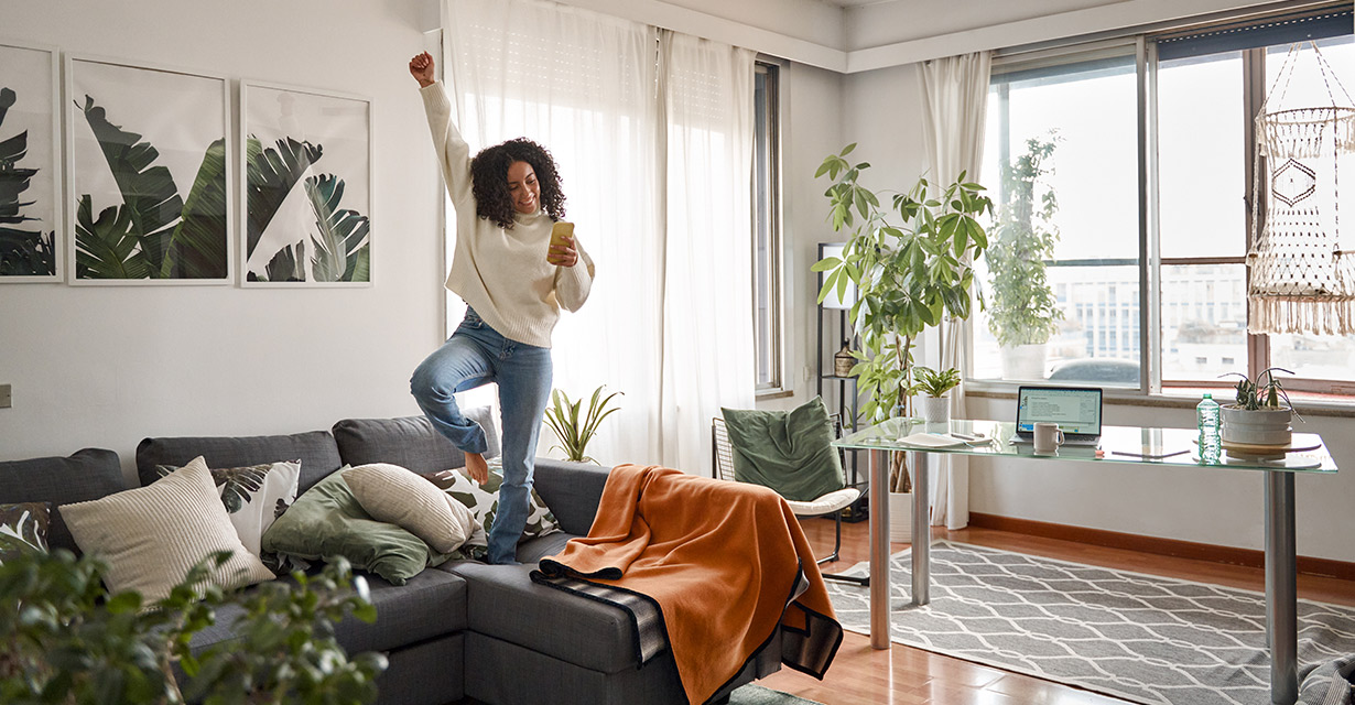 A woman jumping up on her couch and texting