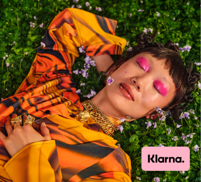 一个时髦的年轻女子懒洋洋地躺在田野里，角落里贴着Klarna的标志