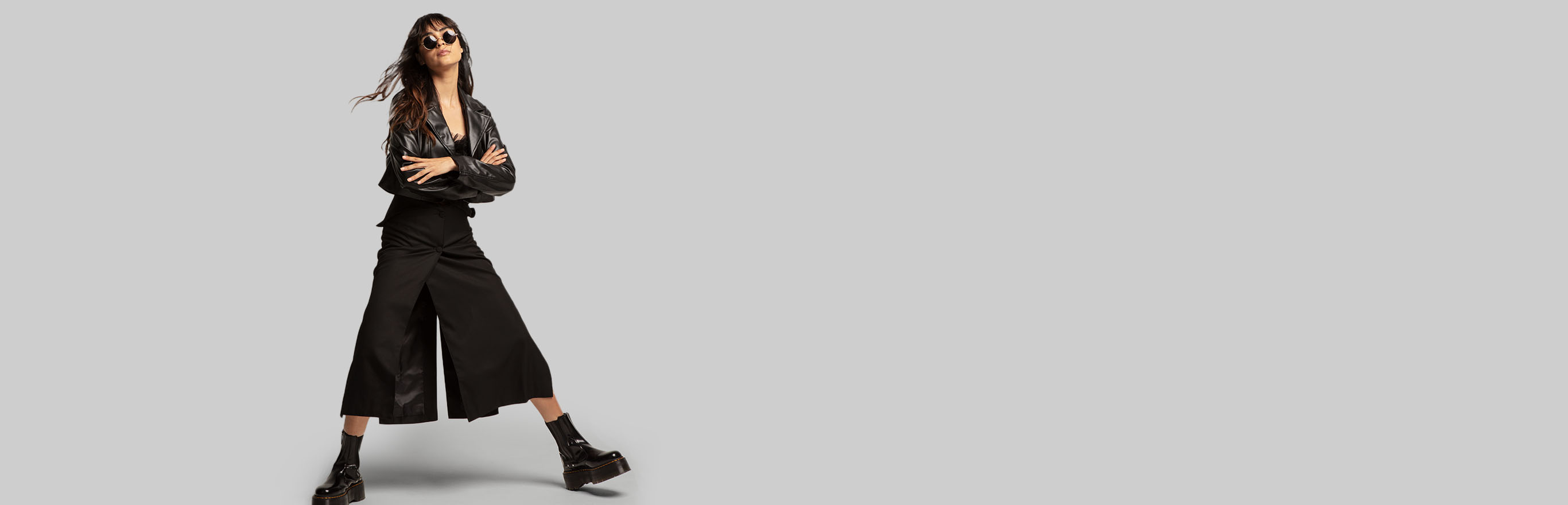 一位年轻女子穿着黑色皮夹克，黑色加乌乔裤子和黑色厚底靴
