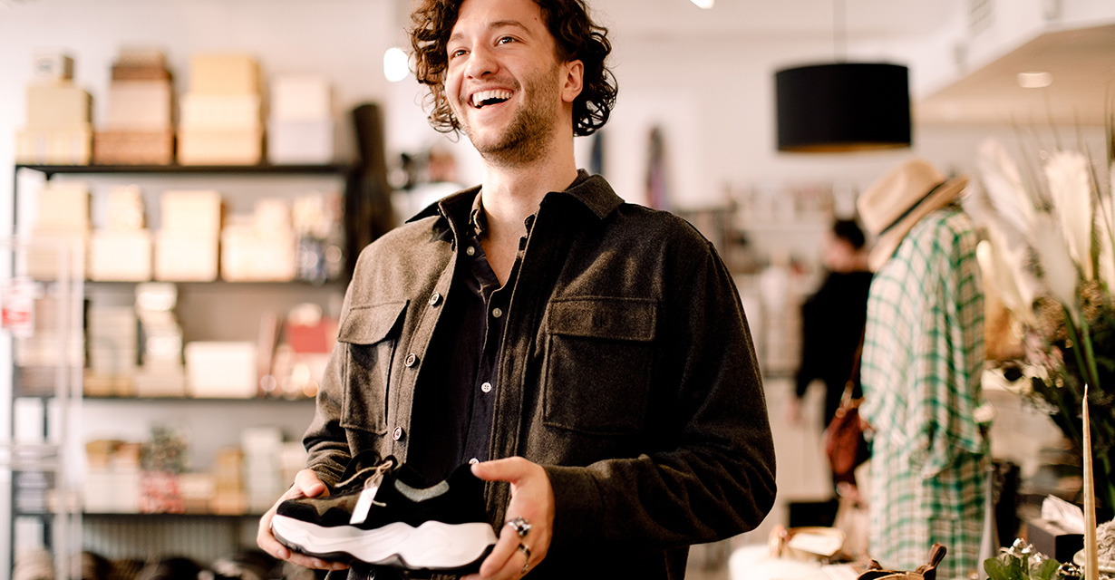 A smiling man holding a shoe in a store