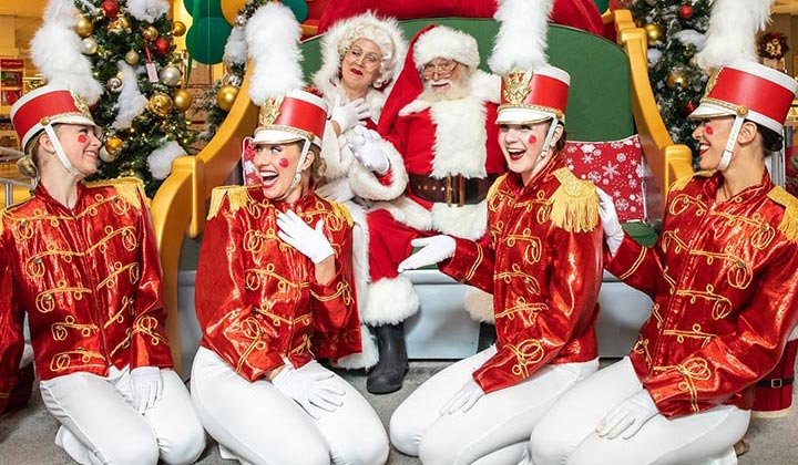 Santa and Mrs. Claus surrounded by additional holiday entertainers in costume