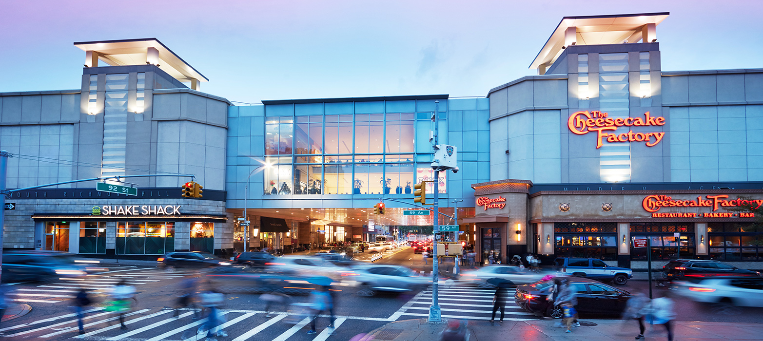 Traffic passing by Queens Center at dusk