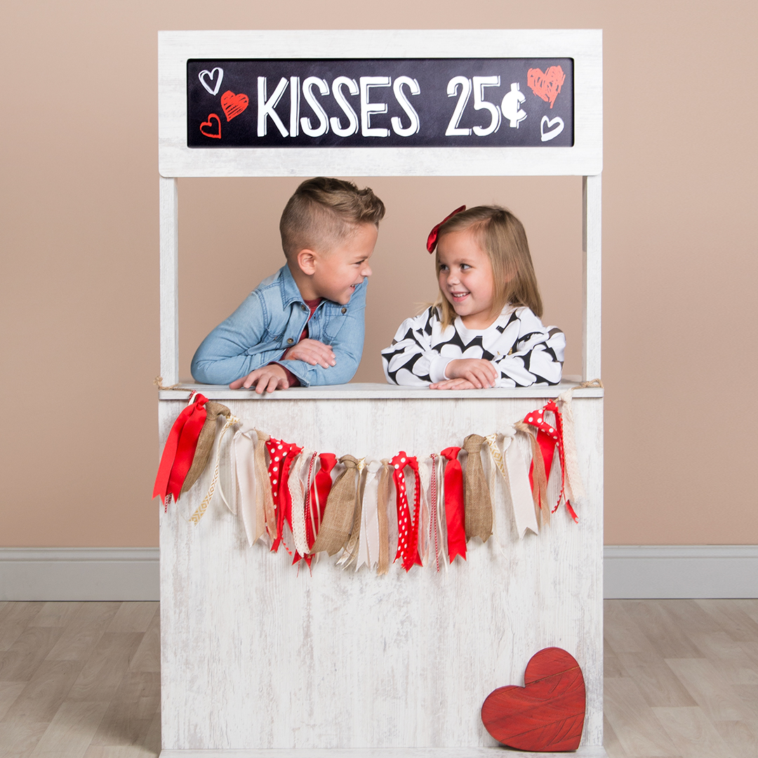 Two children posing at a mini prop stand for Valentine's Day.