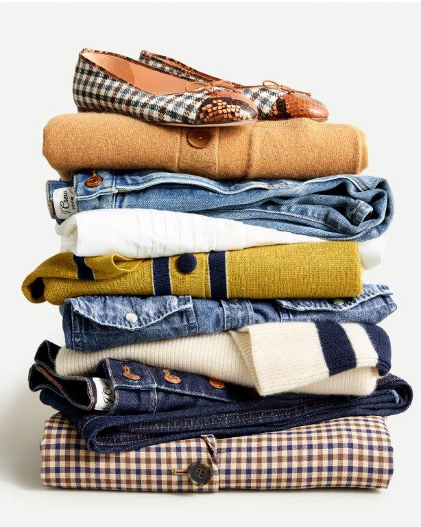 Clothes stacked on top of each other with a pair of women's flats (shoes).