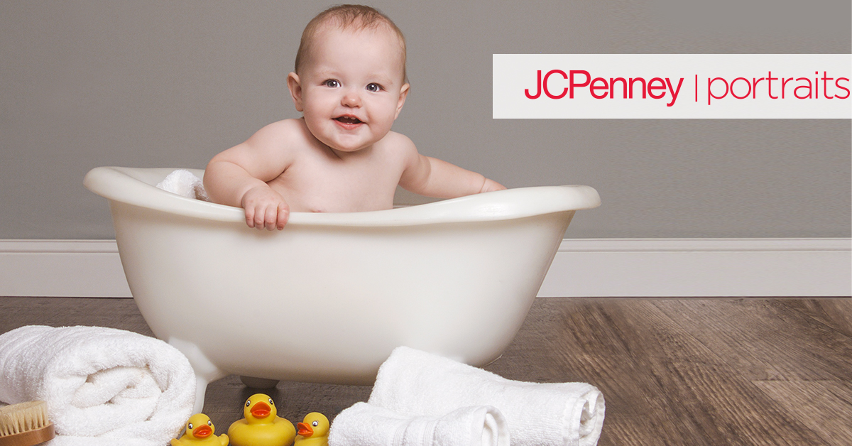 Baby sitting in white bath tub surrounded by ducks and bath towels