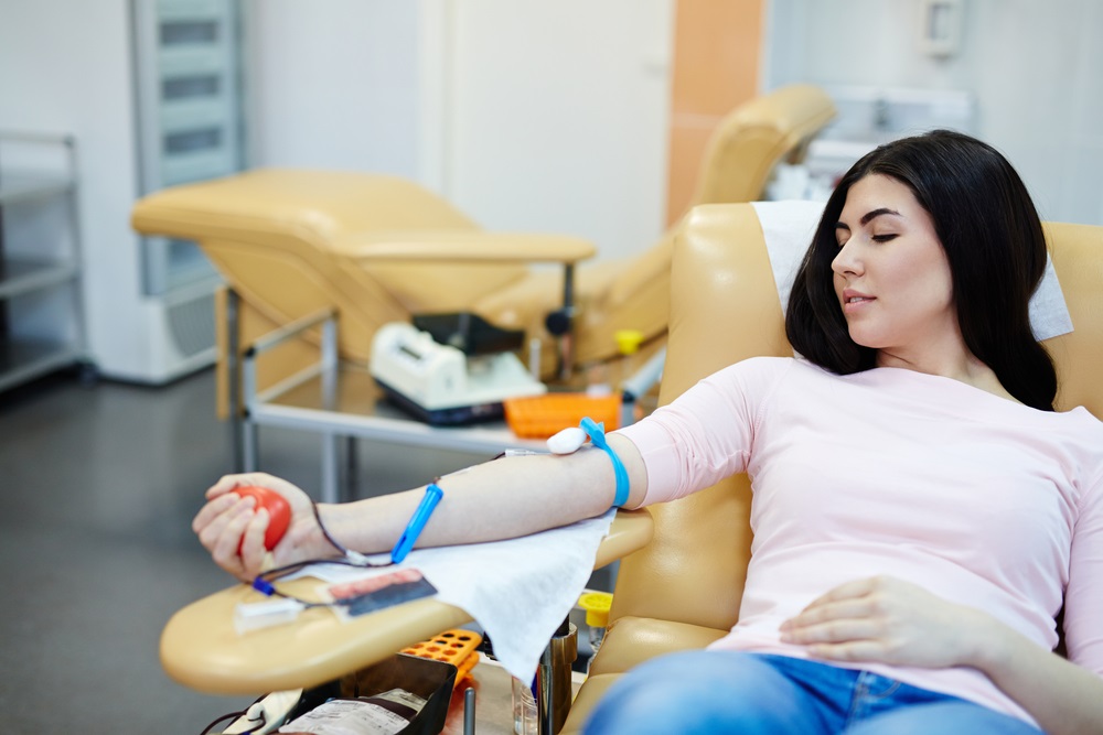 woman lying on table donating blood squeezing a stress ball