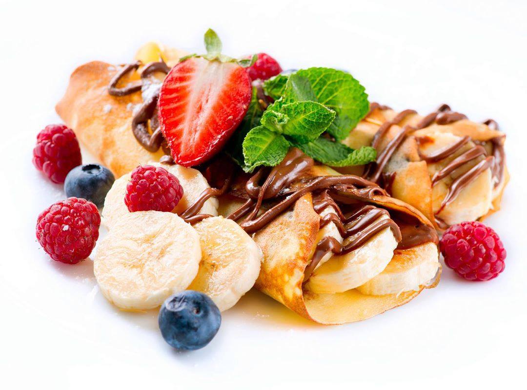 Closeup of crepes with berries, bananas and Nutella