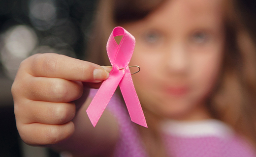 Young girl holding pink ribbon.