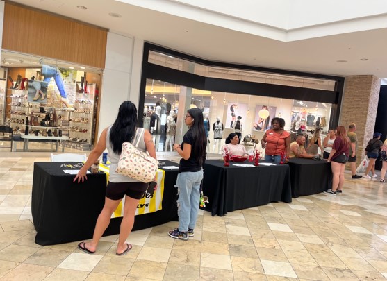 Job fair with tables and retailers talking to people. 