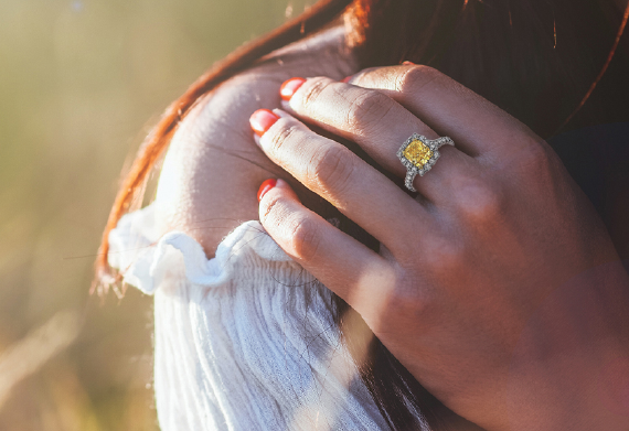 Woman's hand on her shoulder with a yellow diamond ring by IberJoya. 