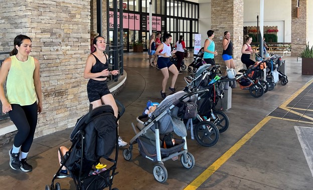 A group of moms working out with their babies in strollers in front of them. 