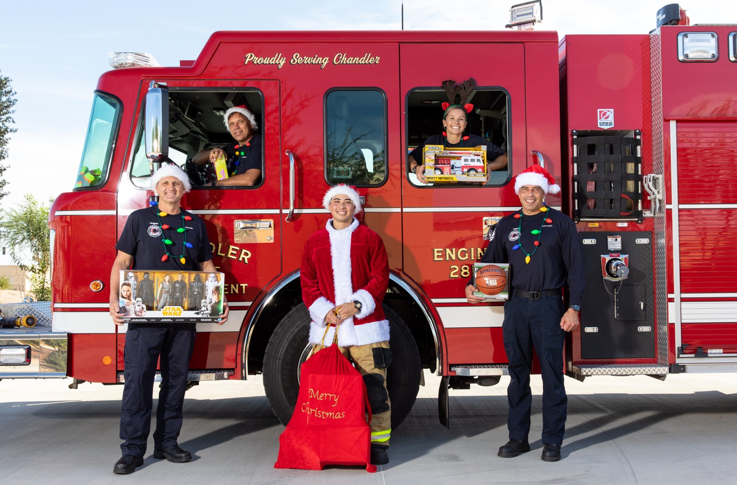 Chandler Fire fighters holding toys in front of a fire truck.