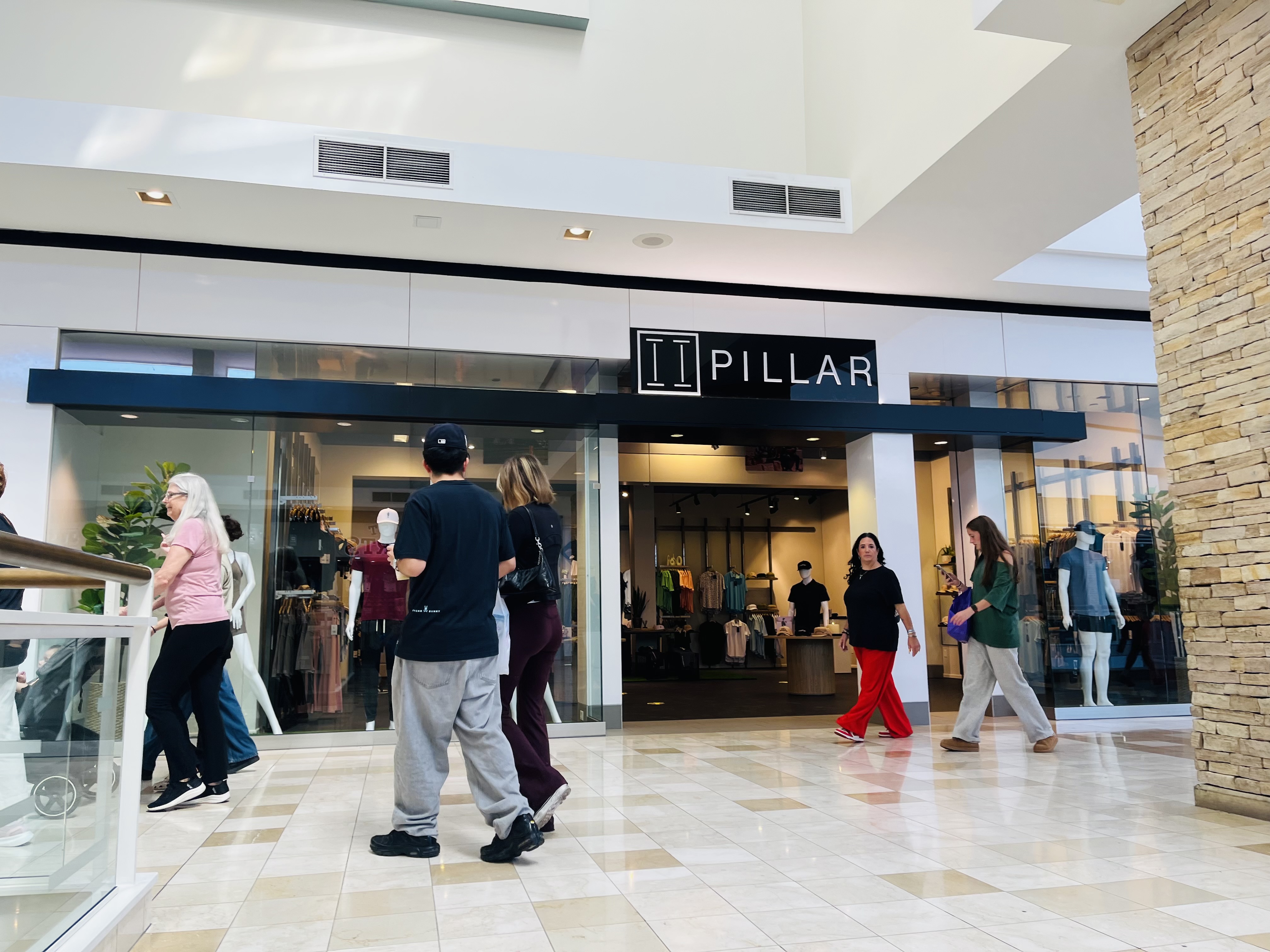 Shoppers walking by the outside of a store named Pillar.