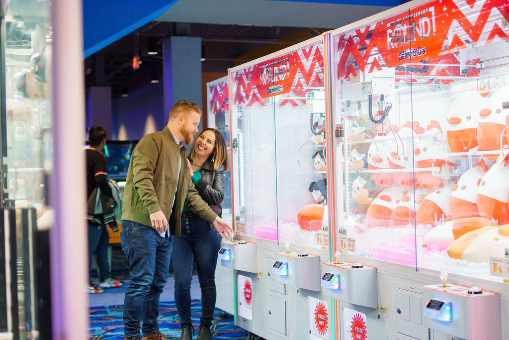 A couple playing a claw arcade game. 