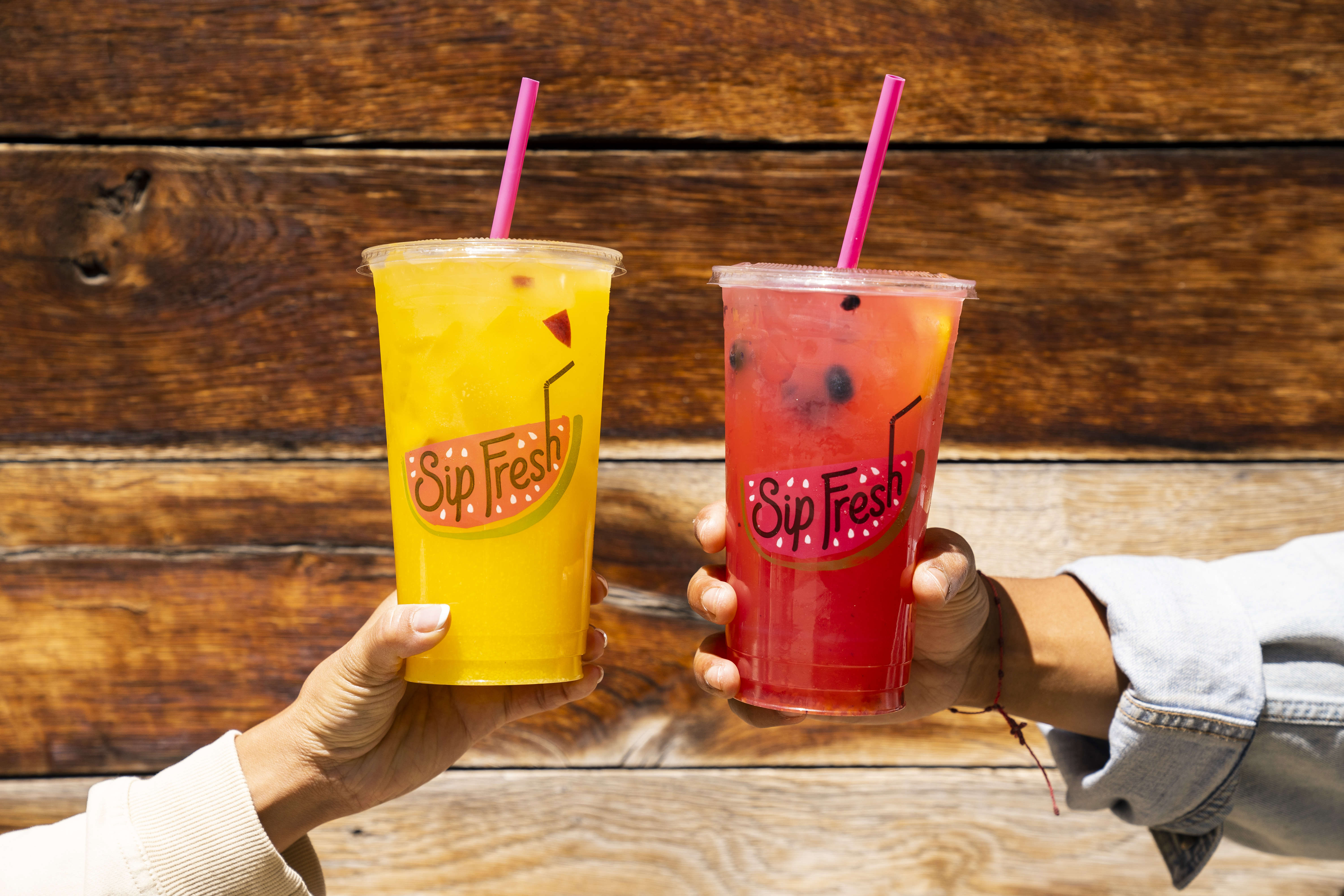 two people holding sip fresh cups with juice, cheers-ing. 