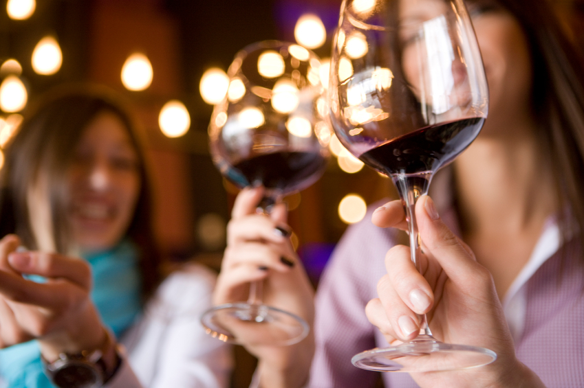 2 wine glasses with red wine and a blurred background of 2 women. 