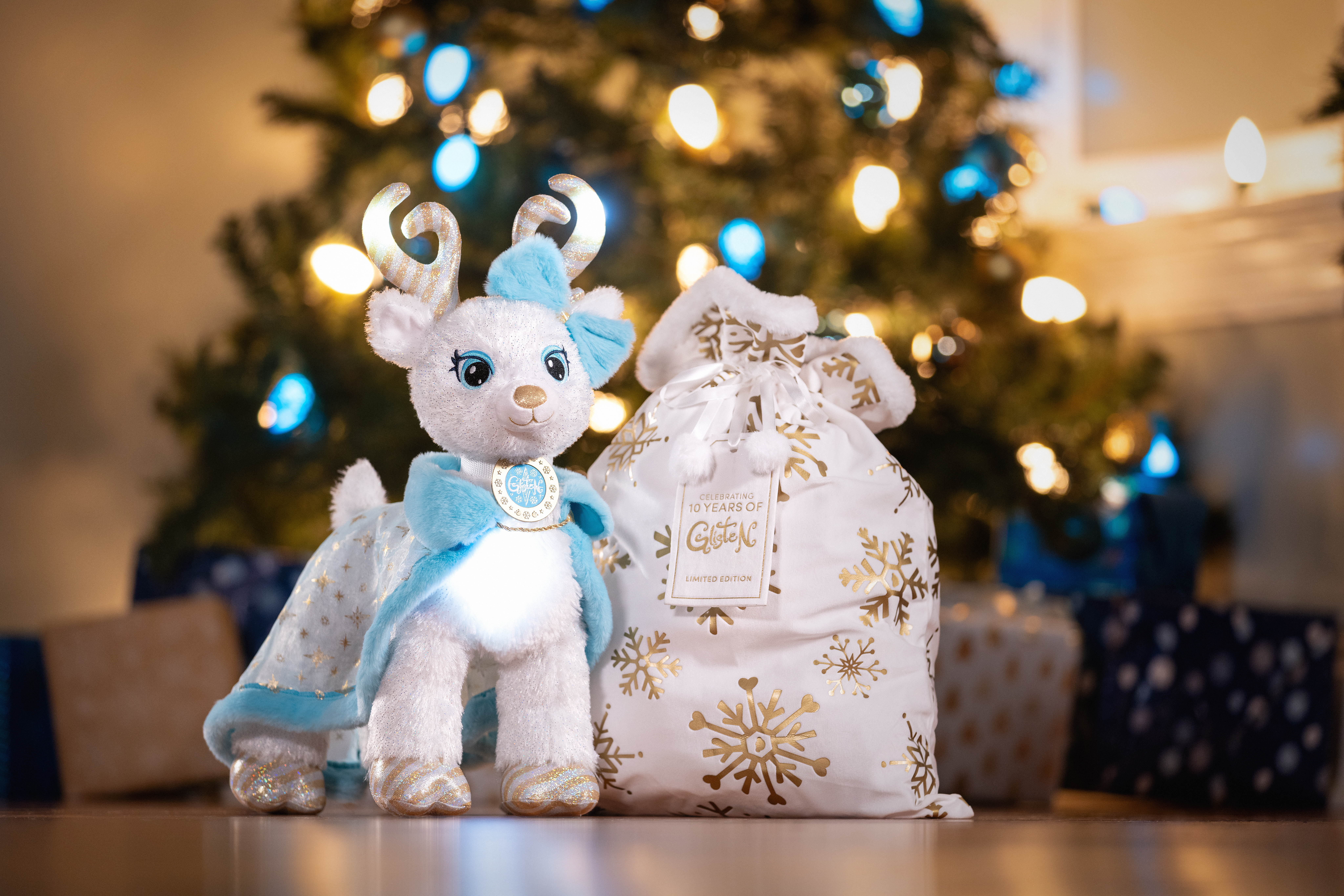 Christmas tree background with white and blue holiday reindeer with a gift bag