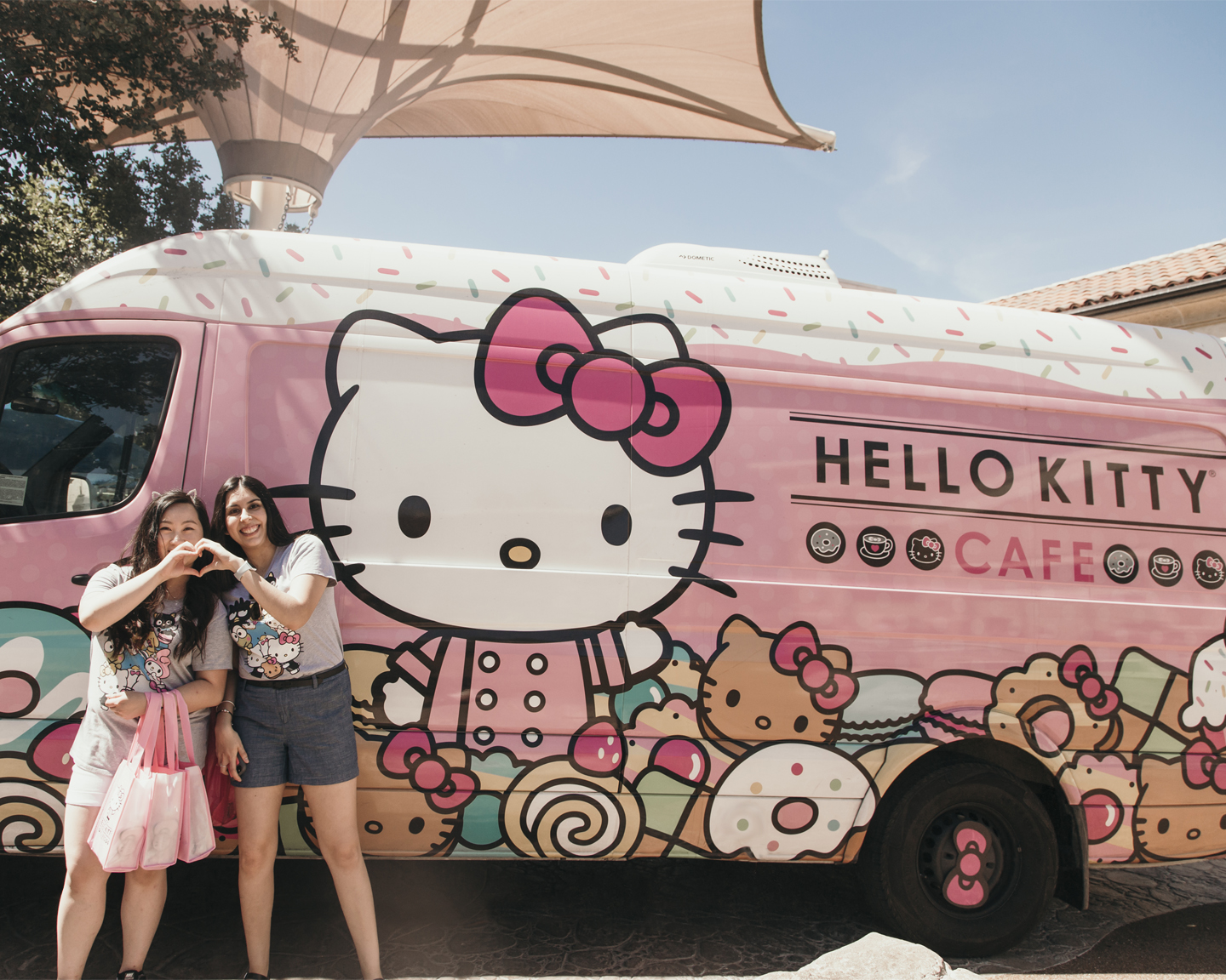 Two women making a heart with their hands in front of the Hello Kitty Cafe Truck 