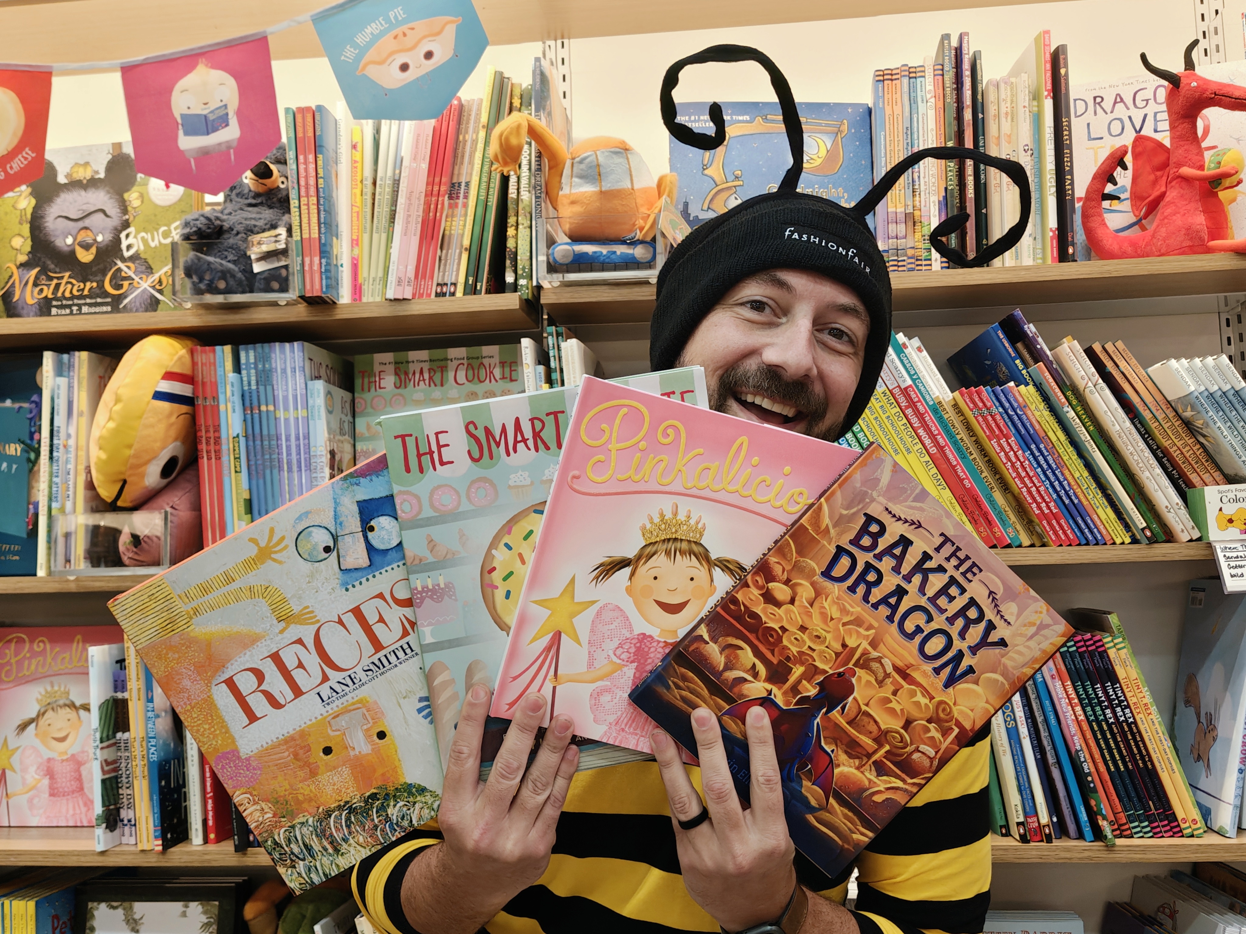 Man in a bee costume holding up several books