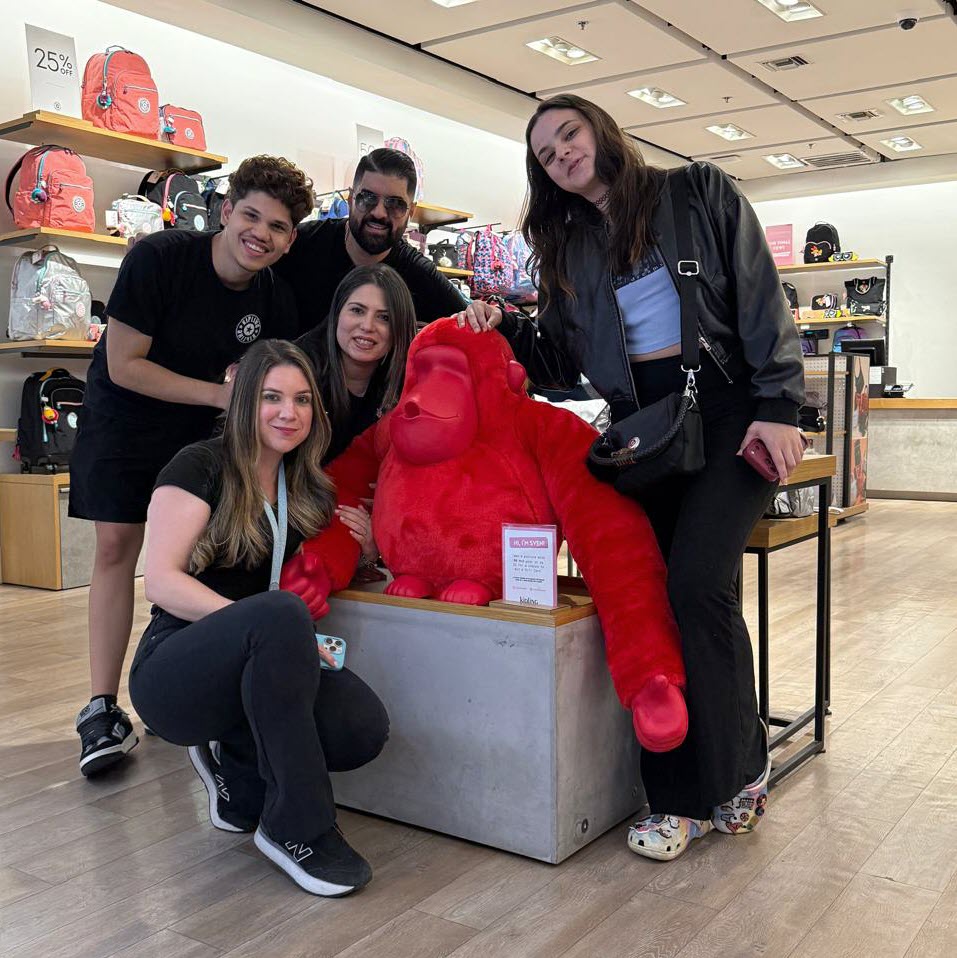 Kipling store associates taking a photo with Sven in a Kipling store.  