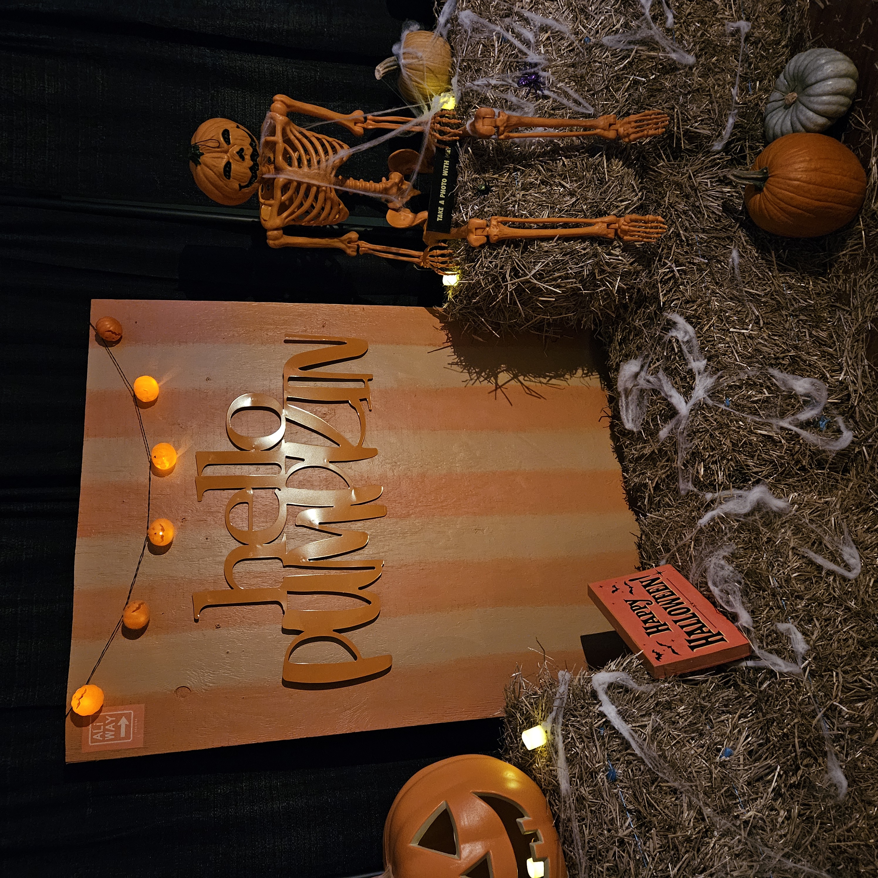 Pumpkin patch with illuminated jack-o-lanterns, straw bales, and other Halloween decor