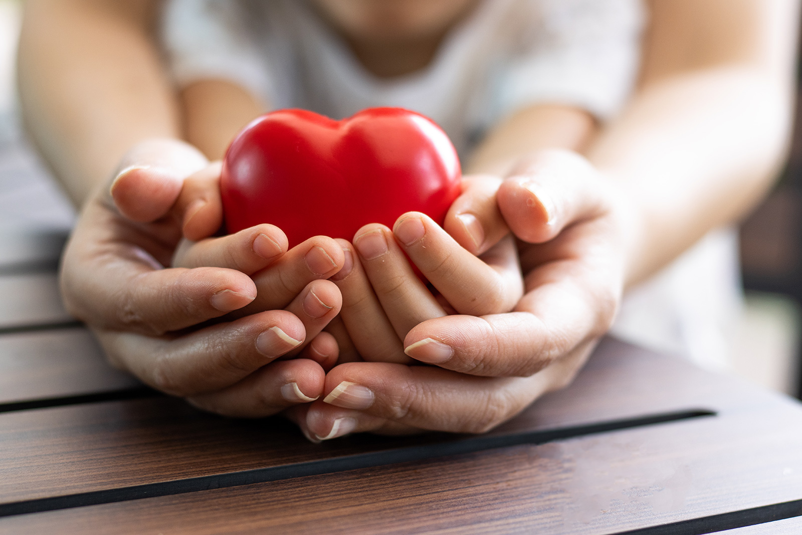 Two pair of hands holding a heart