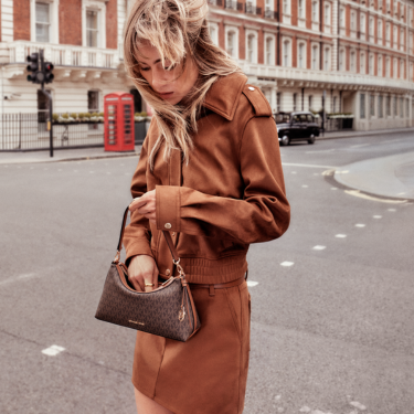 Woman standing on a street looking into her Michael Kors bag