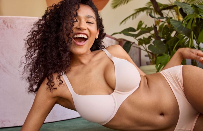 Woman wearing a pink bra and panty set and smiling.