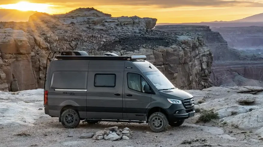 Camper van on top of a canyon with the sunset in the background