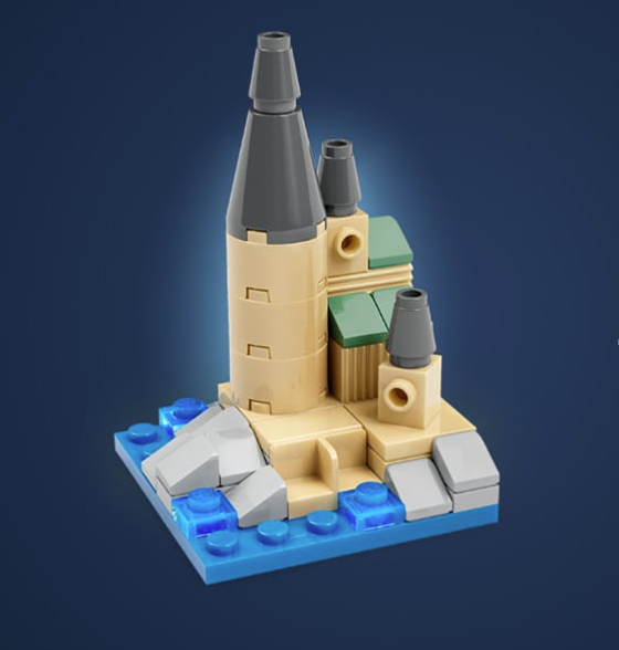Mini LEGO castle build with tan towers, gray rooftops, rocky details, and blue water pieces on a dark blue background.