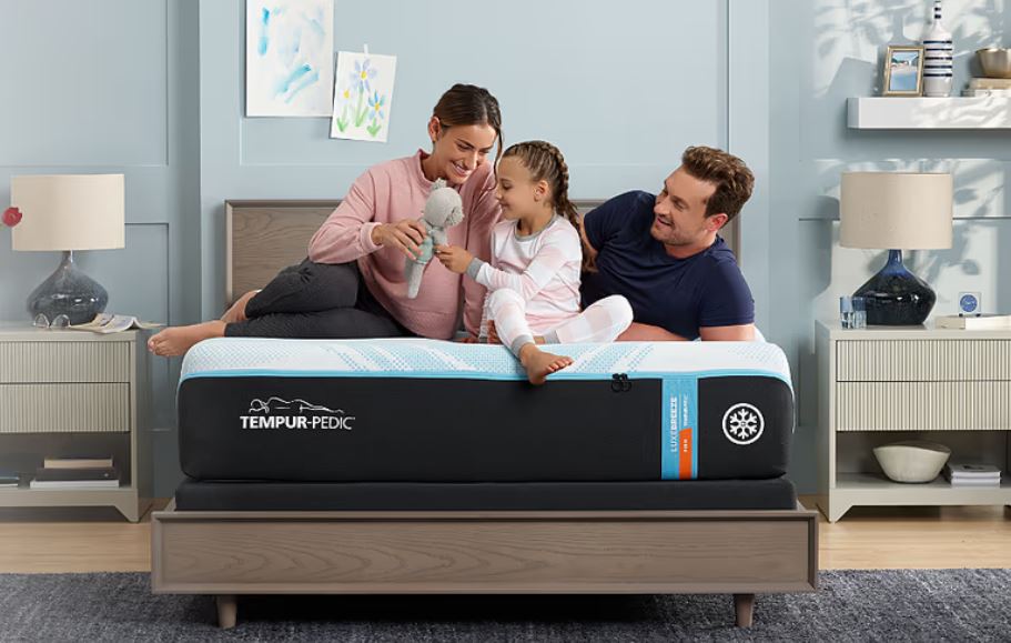 Family of 3 sitting on top of a Tempur-Pedic mattress 