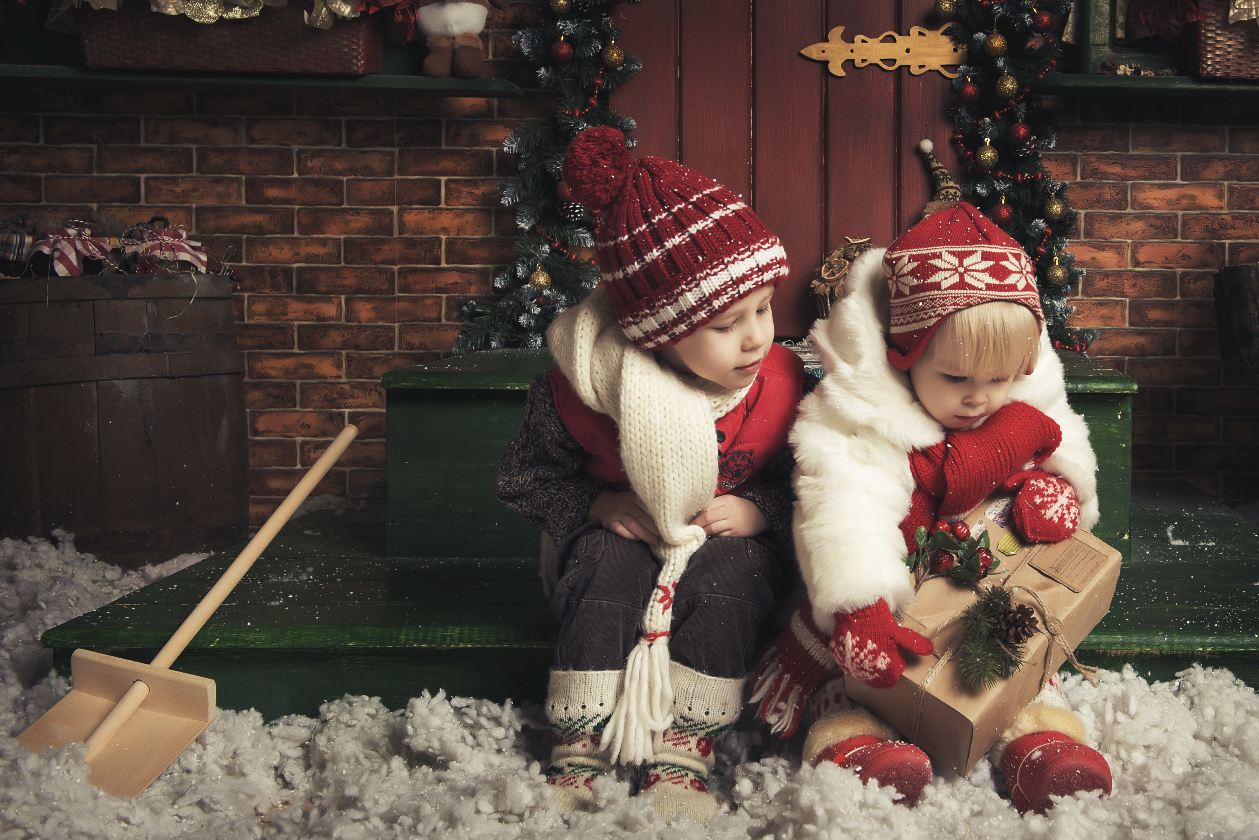 Two children with coats haps gloves sitting on porch and snow