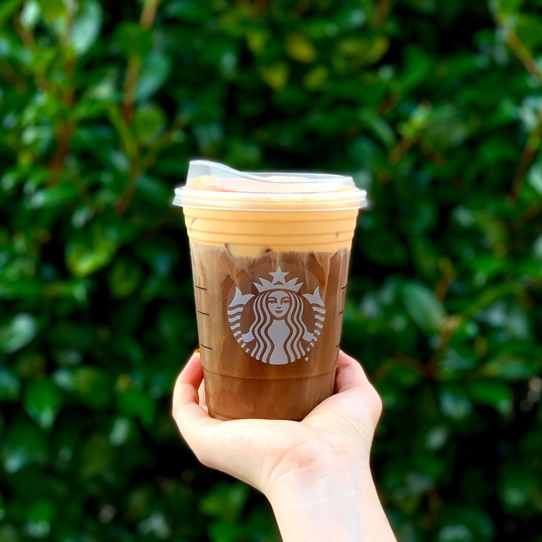 Hand with a Starbuck Cub filled with cold brew coffee