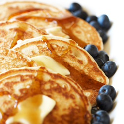Stack of pancakes with butter, syrup and blueberries