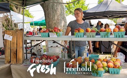 woman selling peaches at a Farmers Market. Wording on photo says: "Freehold Fresh" and "Freehold Raceway Mall".