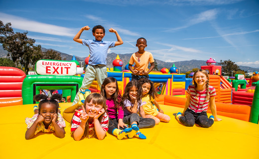 group of children sitting and standing on a bounce playground