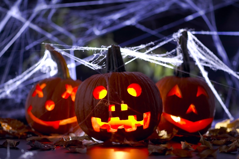 Three illuminated carved pumpkins with spider webs