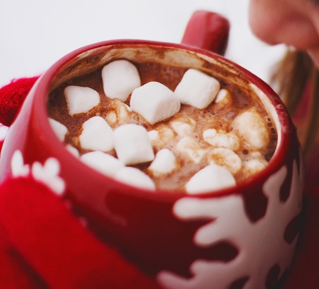 Person drinking hot chocolate out of a red snowflake cup