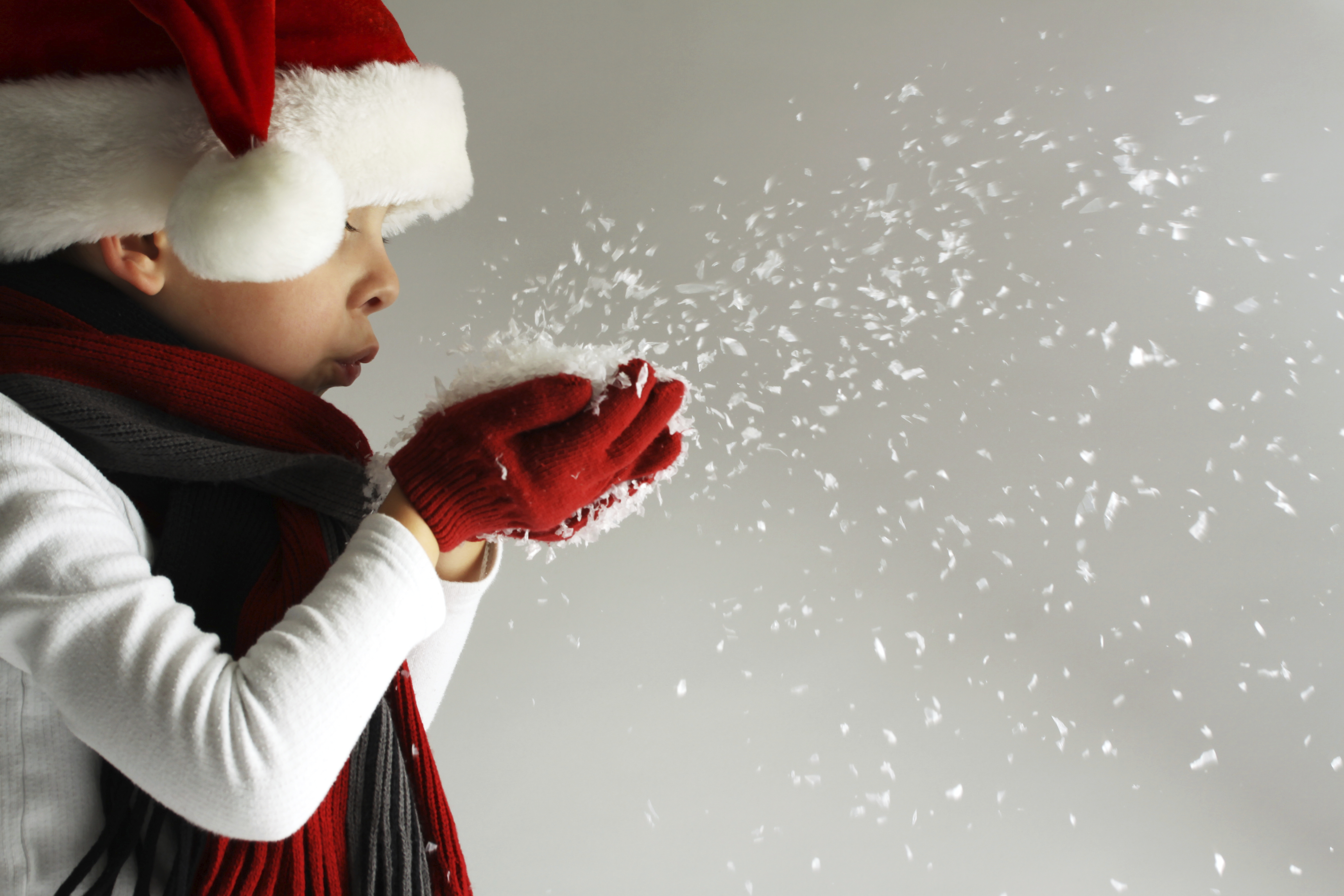 Child with hat, gloves and scarf blowing snow
