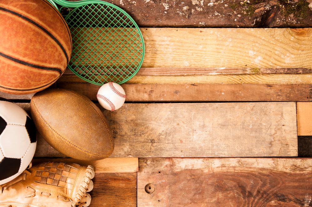 Sports equipment on a wood floor - basketball, Soccer Ball, Tennis Racket, Foot Ball, Glove and Baseball