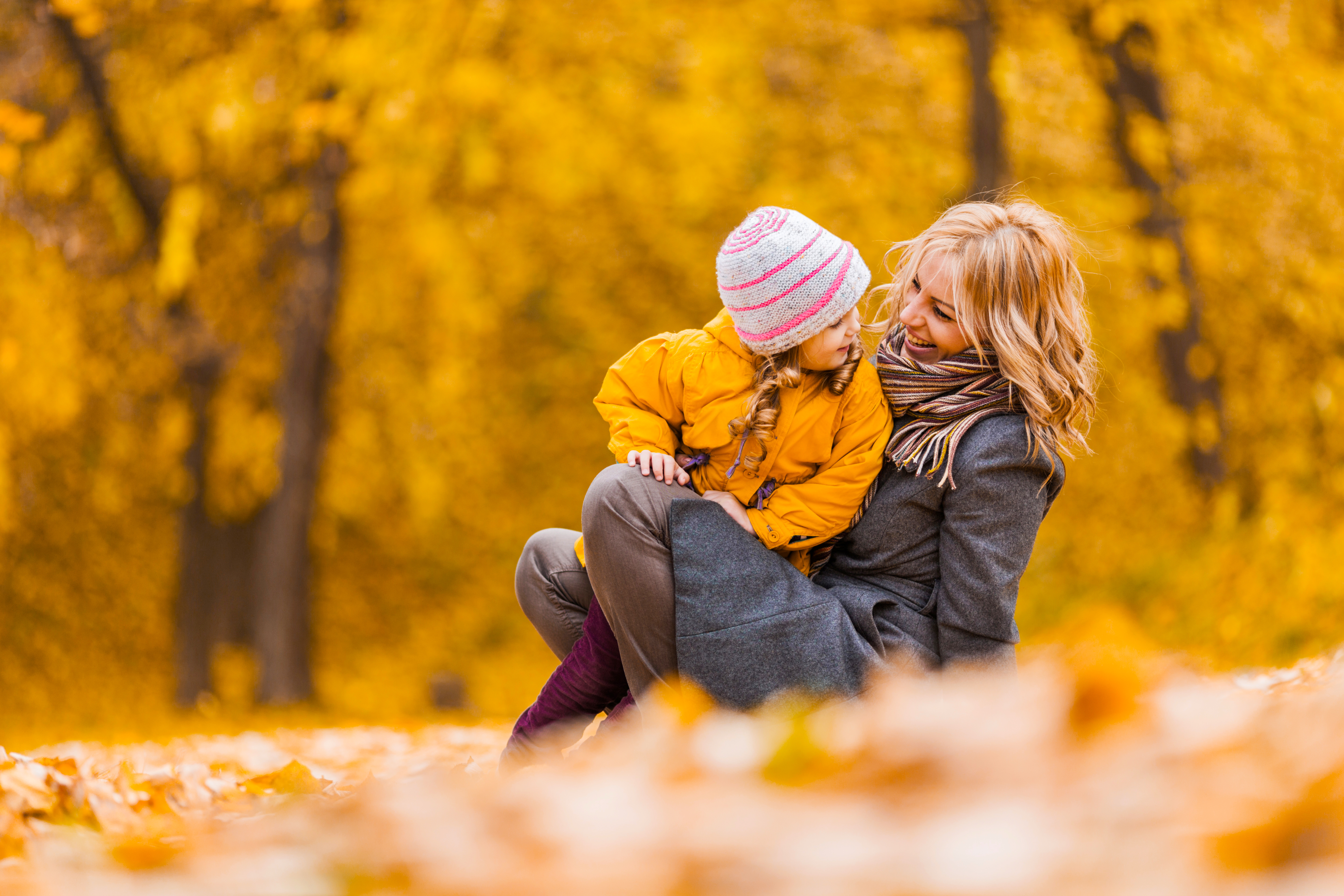 image of mother and child looking at each other outside with fall leaves and trees in the background