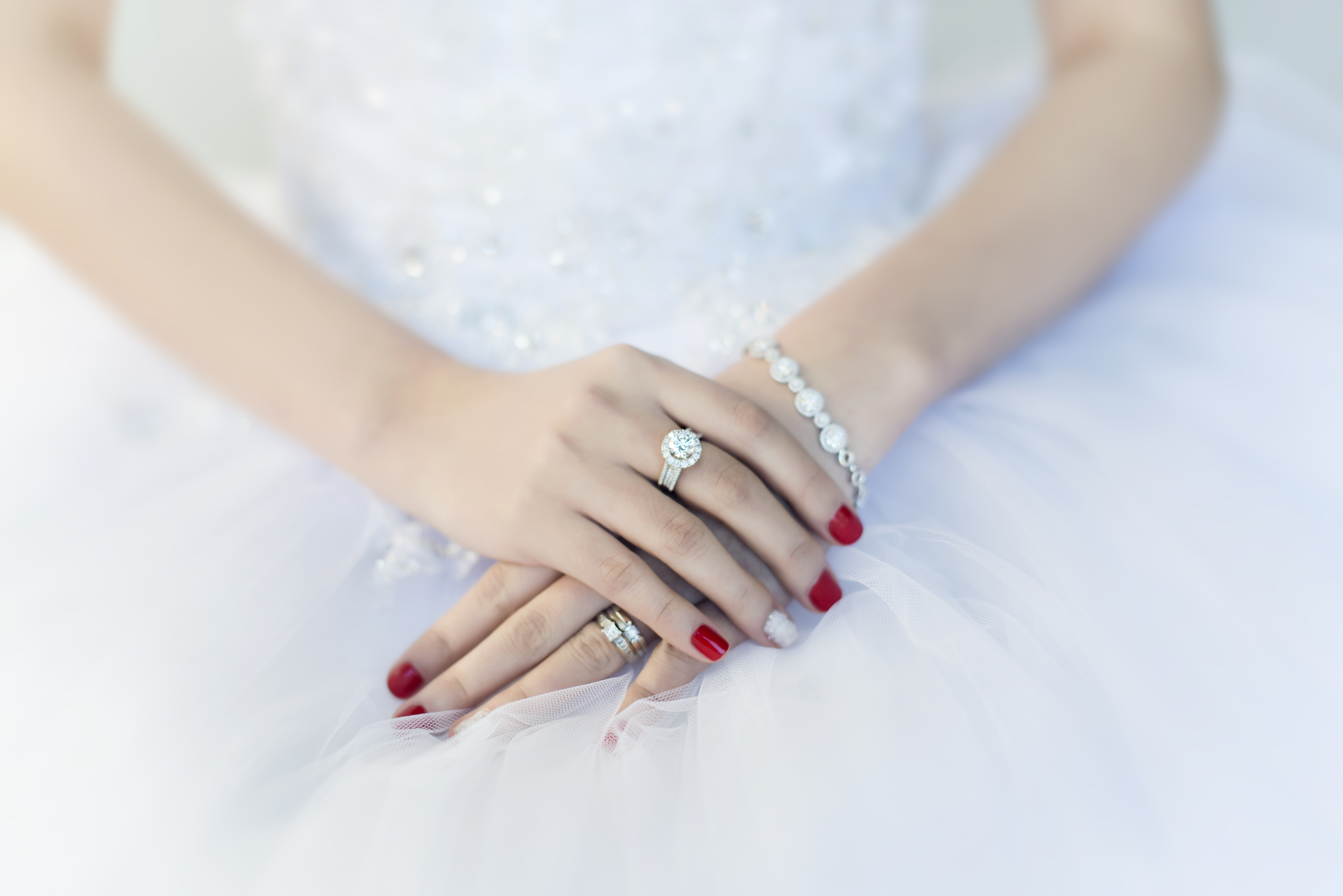 arms and hands with nails painted red and glitter white with rings and bracelets with diamonds 