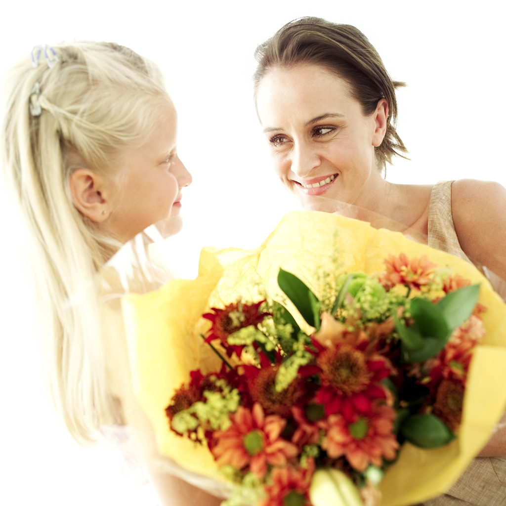 Image shows a mother and daughter holding a bouquet of flowers. 