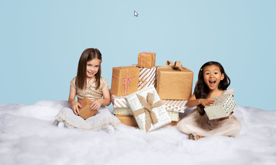 Two little girls on fake snow with pile of gifts